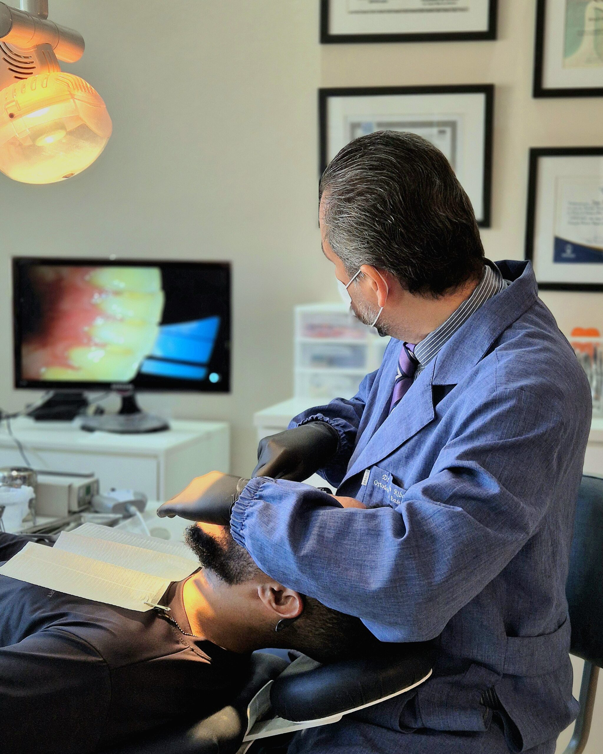 Dr. João Ribeiro em atendimento clínico com câmera intraoral na Versatta Odontologia