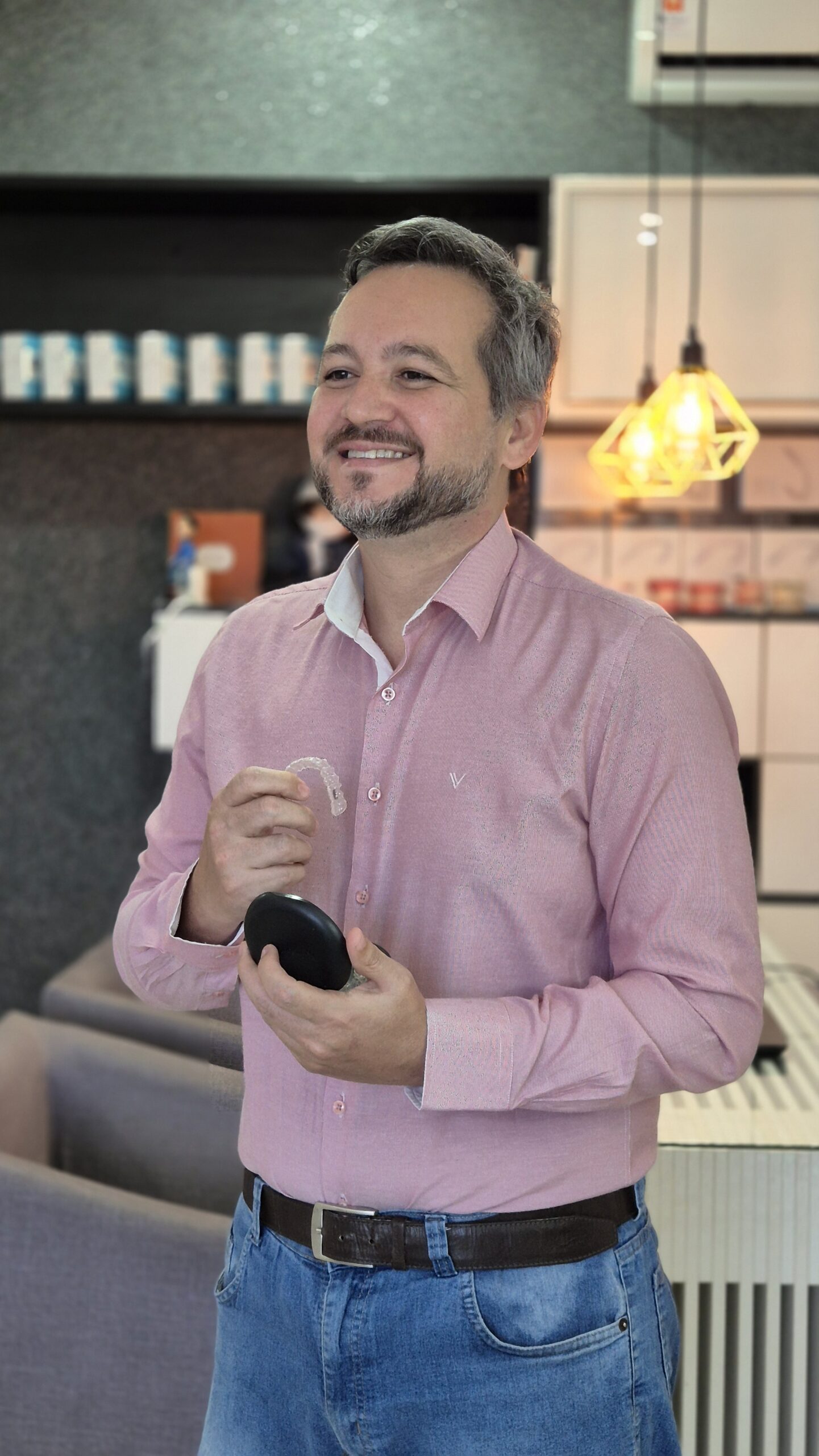 Dr. João Ribeiro, dentista em Petrolina e Juazeiro BA, sorrindo com um alinhador Invisalign na mão
