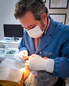 Dr. João Ribeiro, especialista em Ortodontia, realizando procedimento odontológico em paciente no consultório da Versatta