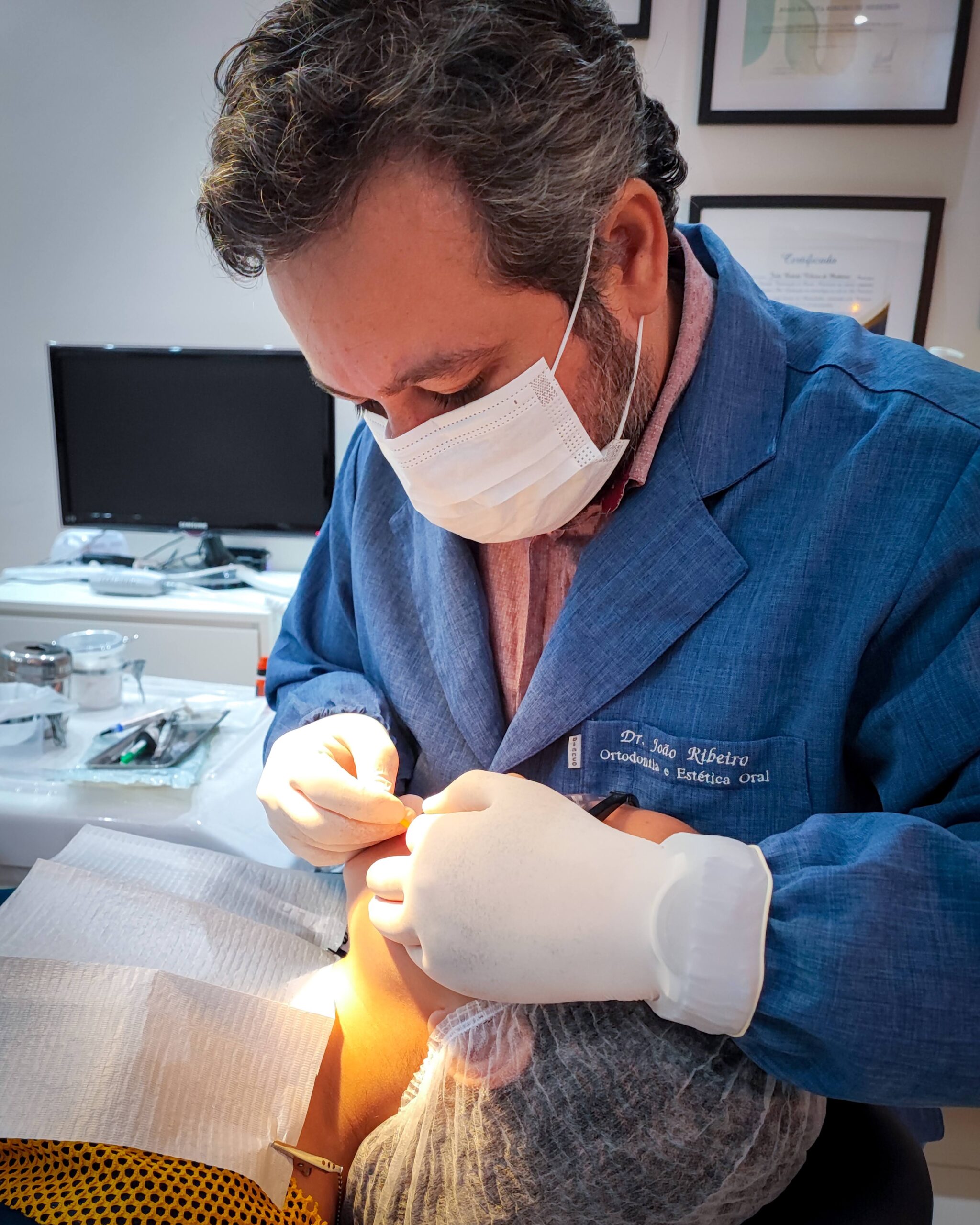 Dr. João Ribeiro, especialista em Ortodontia, realizando procedimento odontológico em paciente no consultório da Versatta